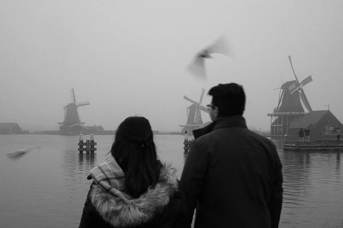 asian couple enjoying the windmill view of Zaanse Schans Netherlands in black and white