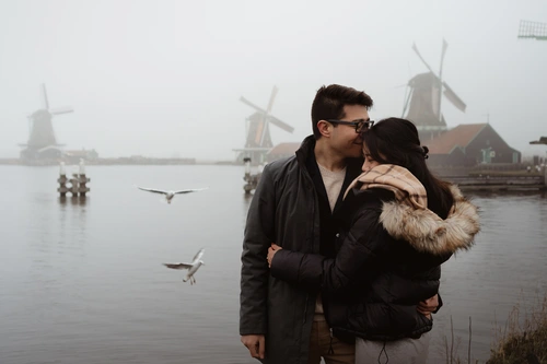 lovely couple at photoshoot location with seagulls flying around the misty landscape of the Netherlands