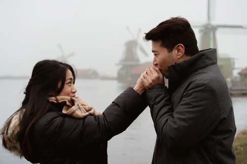 a man warms up his girlfriend's hands during a misty and cold winter day in the Netherlands