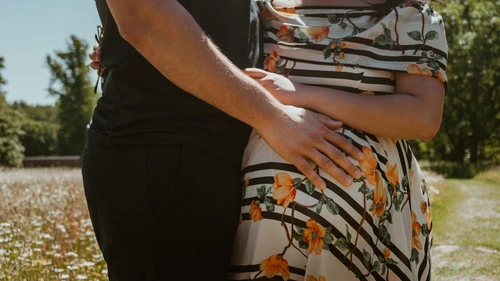 a future father's hand touching the belly of his pregnant wife