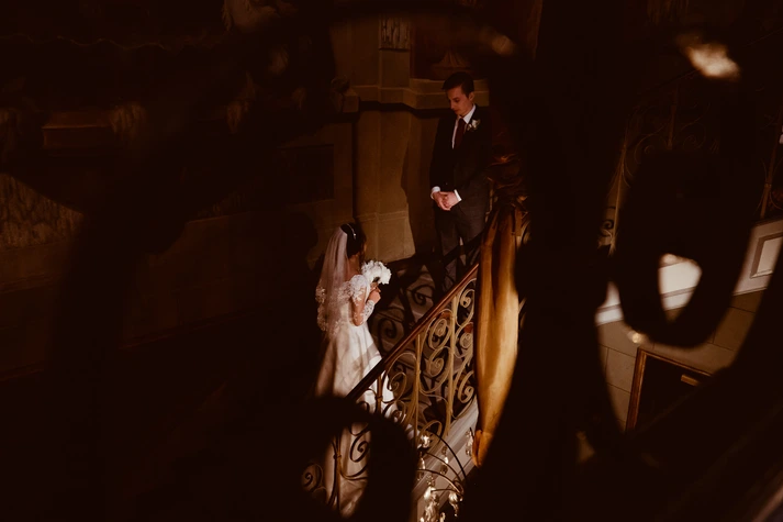 bride with flowers climbing stairs to her newly wedded husband