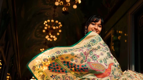 asian woman presents her handmade scarf with historical chandeliers in the background