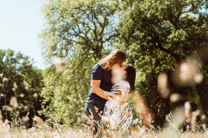 interracial couple kissing in the flower field while hugging each other