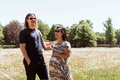 a couple laughing in a daisy field on a sunny day