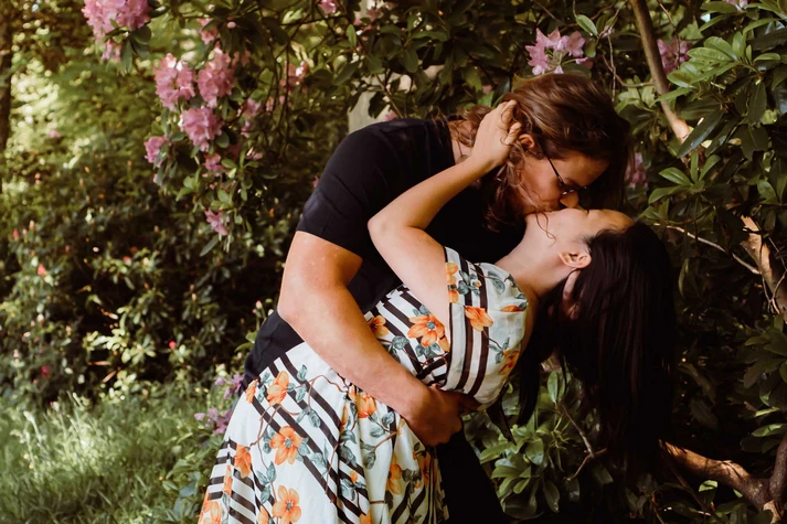 a couple kissing with a flower background in the forest