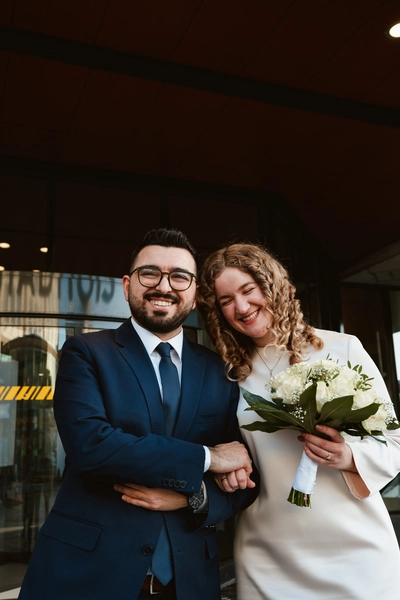 A newlywed couple walks hand in hand out of the Stadhuis Almere, beaming with joy on their special day. Their radiant smiles capture the love and happiness shared during their wedding ceremony – by DiscussTomorrow wedding photography