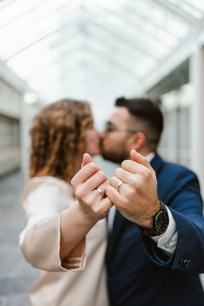 Experience a creative and modern wedding portrait captured by our photography service at gemeente Almere. The couple's wedding bands take center stage, as they share a romantic kiss in the background, resulting in a timeless and stunning memory of their special day.