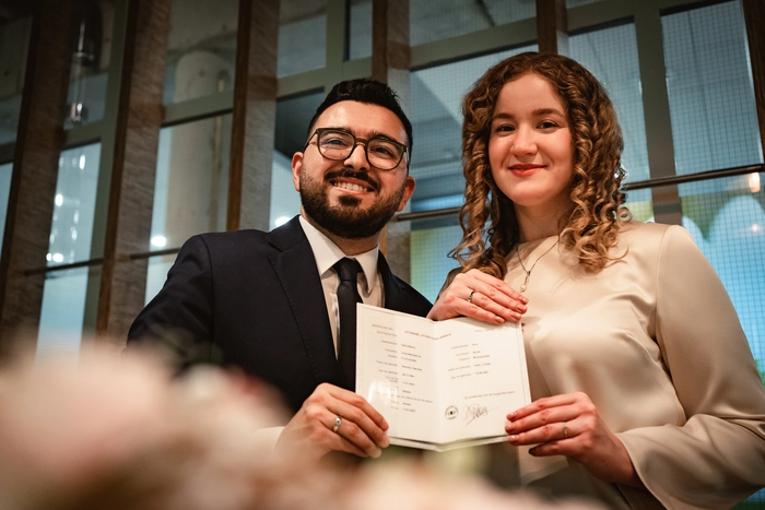 A happy couple proudly displays their wedding book and bands, a symbol of their love and commitment, after signing the wedding deeds at the gemeente Almere’s Trouwkamer  – by DiscussTomorrow Weddings.