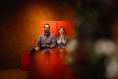 A candid photo of the newlyweds K & R sitting on vibrant red chairs at a modern and cozy venue, ready to be wedded at gemeente Almere. The photo was taken by DiscussTomorrow Photography, showcasing their exceptional skills in capturing candid moments.