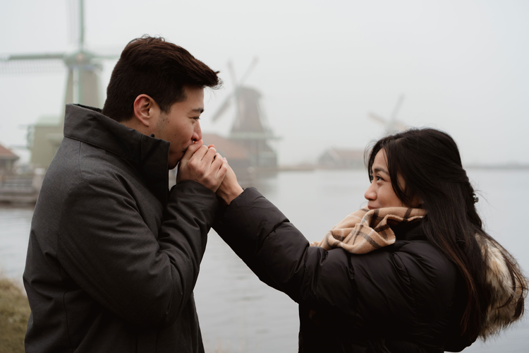 couple looking out over misty water with mills in the background