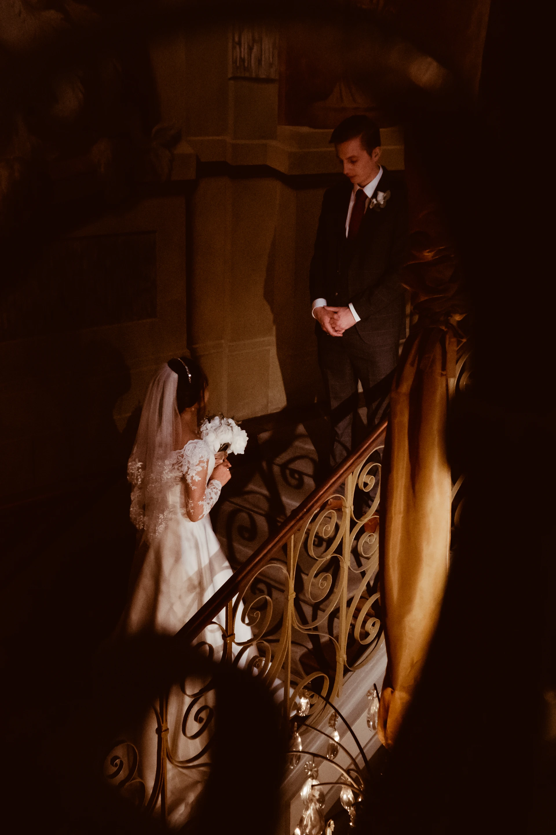 bride with flowers climbing stairs to her newly wedded husband