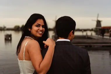 Woman leaning on her partner's shoulder looking into the camera at Sunset photoshoot Zaanse Schans